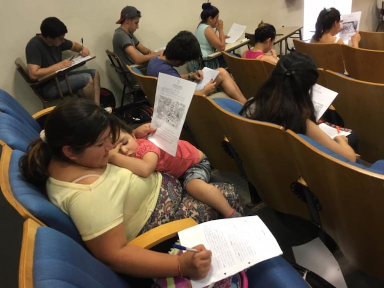 Alicia completó su examen con su beba dormida en brazos.