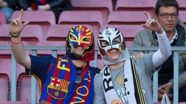 Dos hinchas con distintas camisetas pero unidos en la tribuna.