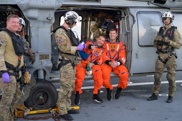 El comandante Reid Wiseman y el astronauta Jeremy Hansen, sentados al borde del helicóptero que los rescató después del amerizaje en el océano Pacífico. (Foto: NASA)