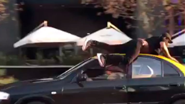 El hombre atropellado intenta agarrase al techo del coche, en Providencia, Chile.