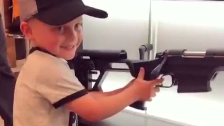 El niño, muy contento, usando un rifle.