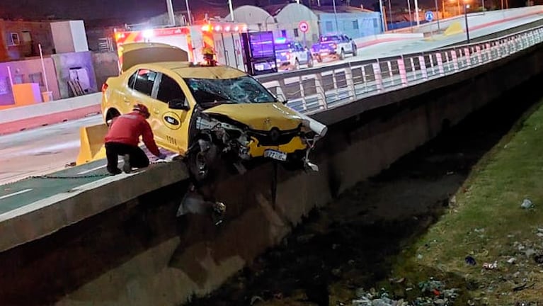 El taxi quedó colgado del puente tras el fuerte impacto contra la moto.