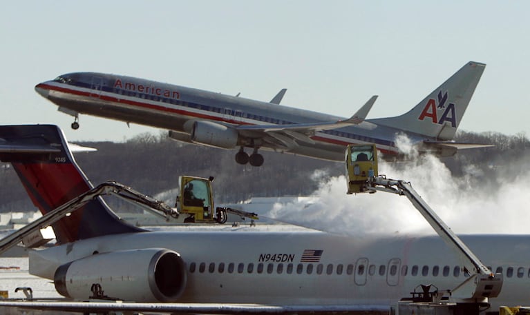 FILE PHOTO: A Delta jetliner (foreground) is de-iced while an American Airlines plane (rear) takes off at Reagan National Airport in Washington January 3, 2014.  REUTERS/Gary Cameron/File Photo