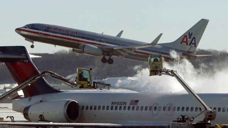 FILE PHOTO: A Delta jetliner (foreground) is de-iced while an American Airlines plane (rear) takes off at Reagan National Airport in Washington January 3, 2014. REUTERS/Gary Cameron/File Photo