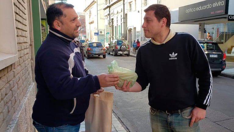 Gastón entrega el pan casero "bien calentito" a uno de sus clientes en el centro. / Foto: ElDoce.tv