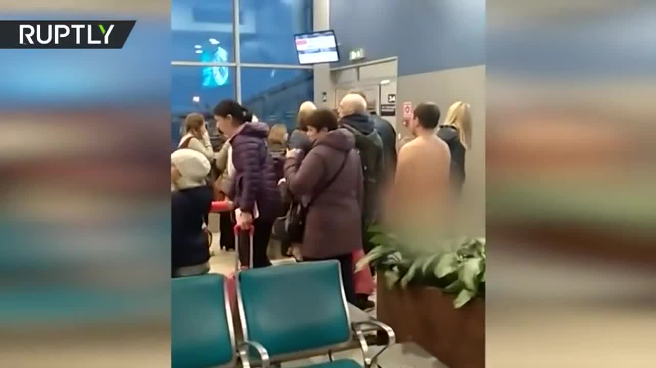 Un hombre desnudo en la fila para subir al avión