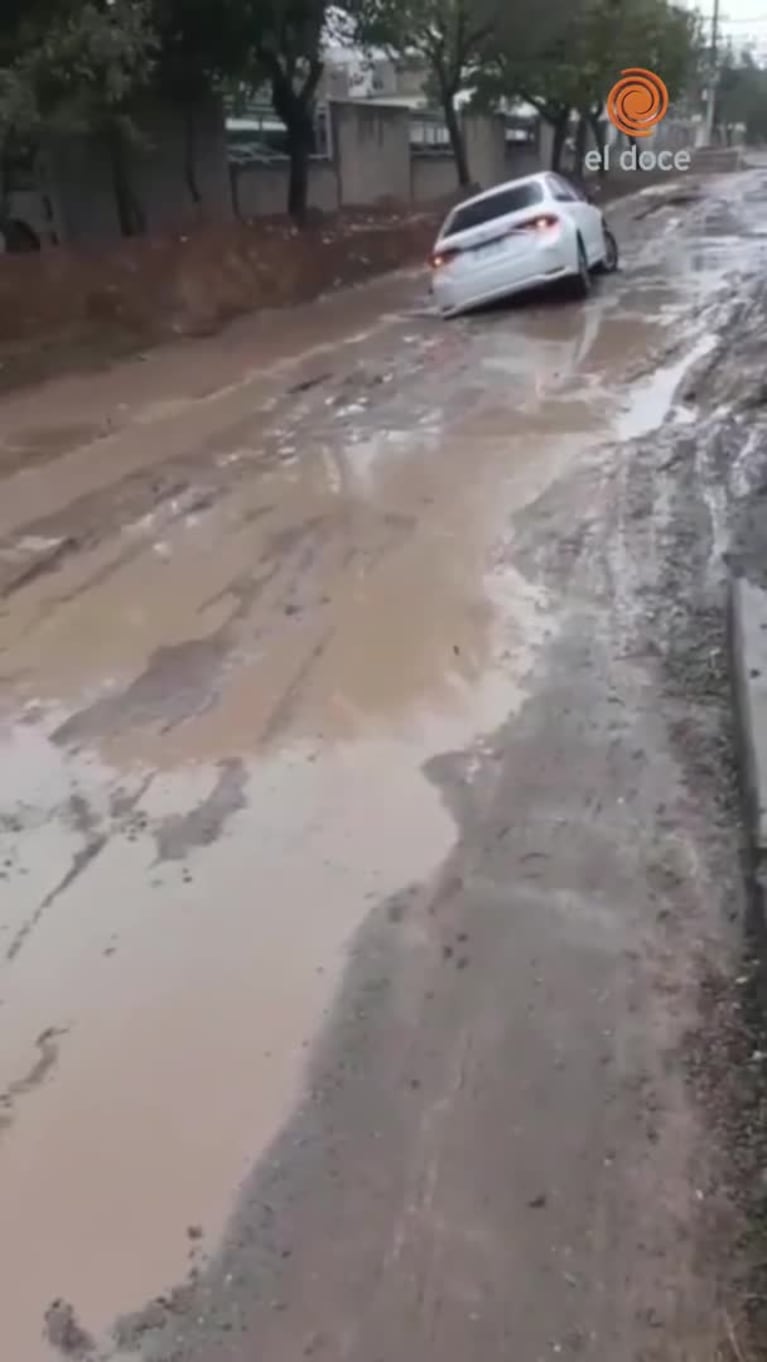 La lluvia agrietó una calle de tierra y un auto se hundió