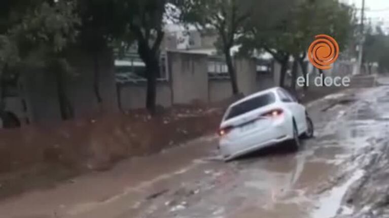La lluvia agrietó una calle de tierra y un auto se hundió