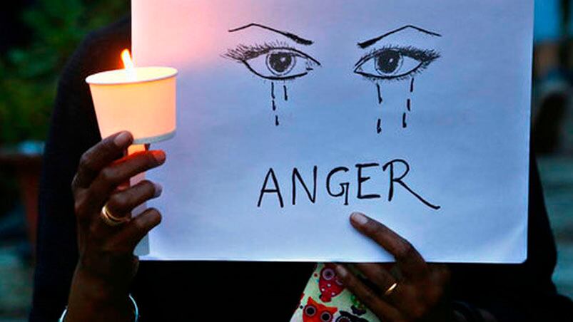 Imagen de una mujer sosteniendo una vela y un cartel que lee "furia" en protesta contra la violencia sexual en India. Foto: AP