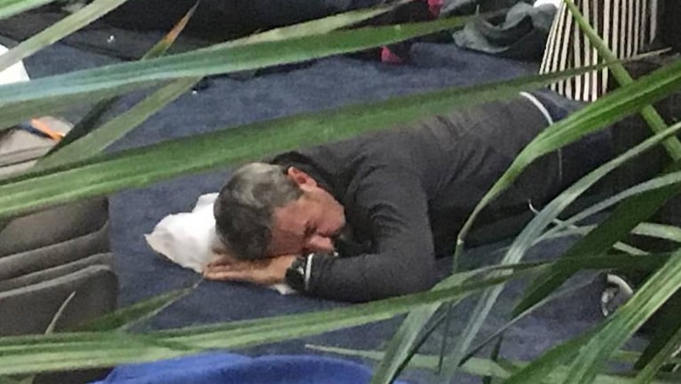 Julio Cobos durmiendo en el piso del aeropuerto.
