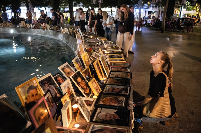 Katya Emelianova kneels beside a portrait of Eden Gez, who was killed at the Nova Festival by Hamas militants in the Oct. 7 attack, in Tel Aviv, Israel, on Tuesday, Oct. 7, 2025. The somber milestone of the second anniversary of the Hamas-led attack on Israel comes with peace talks underway, hostages from the Hamas-led attack still in Gaza, more than 67,000 Palestinians dead and Israel more isolated than ever. (David Guttenfelder/The New York Times)