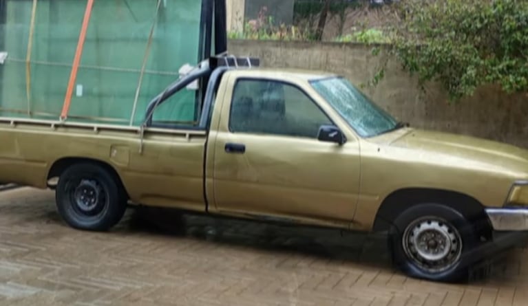 La camioneta es una Hilux dorada modelo 2001.