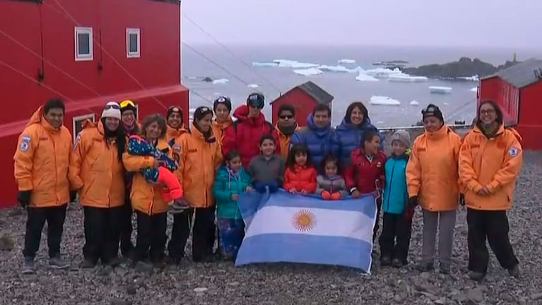 Las familias portando la bandera de Argentina en la Antártida.