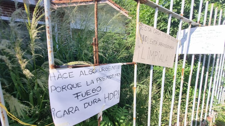 Los carteles que colgaron en la reja de la casa tapada por los yuyos.