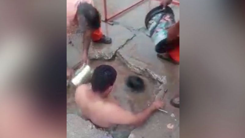 Los empleados trabajando desde el interior del pozo de agua sucia.