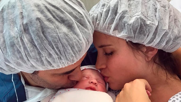 Mariano y Camila besando a la recién nacida. 