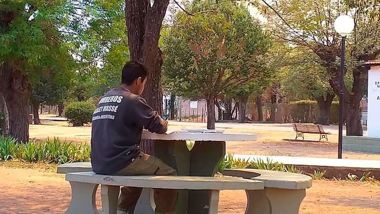 Mauricio Destefani, con celu en mano rindiendo y los libros sobre la mesa de la plaza de Ambul. (Foto: Traslasierra Noticias)
