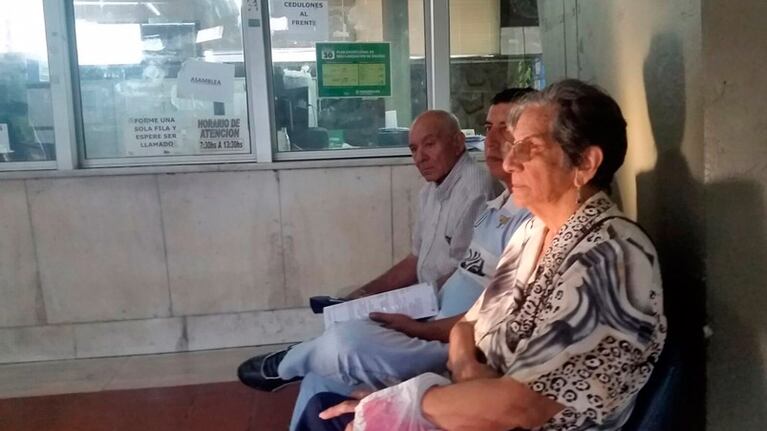Mientras la gente espera, el cartel "asamblea" arriba del que señala el horario.