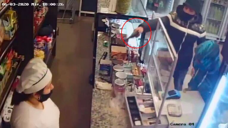 Mientras uno roba la caja registradora, otro apunta con un arma a la trabajadora.