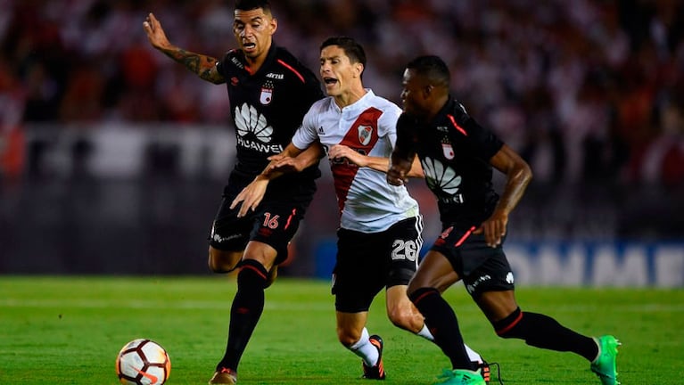 Nacho Fernández lucha contra dos rivales de Independiente Santa Fe. 