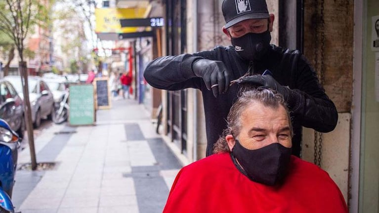 Por las restricciones, un peluquero sacó el sillón a la vereda para atender a sus clientes