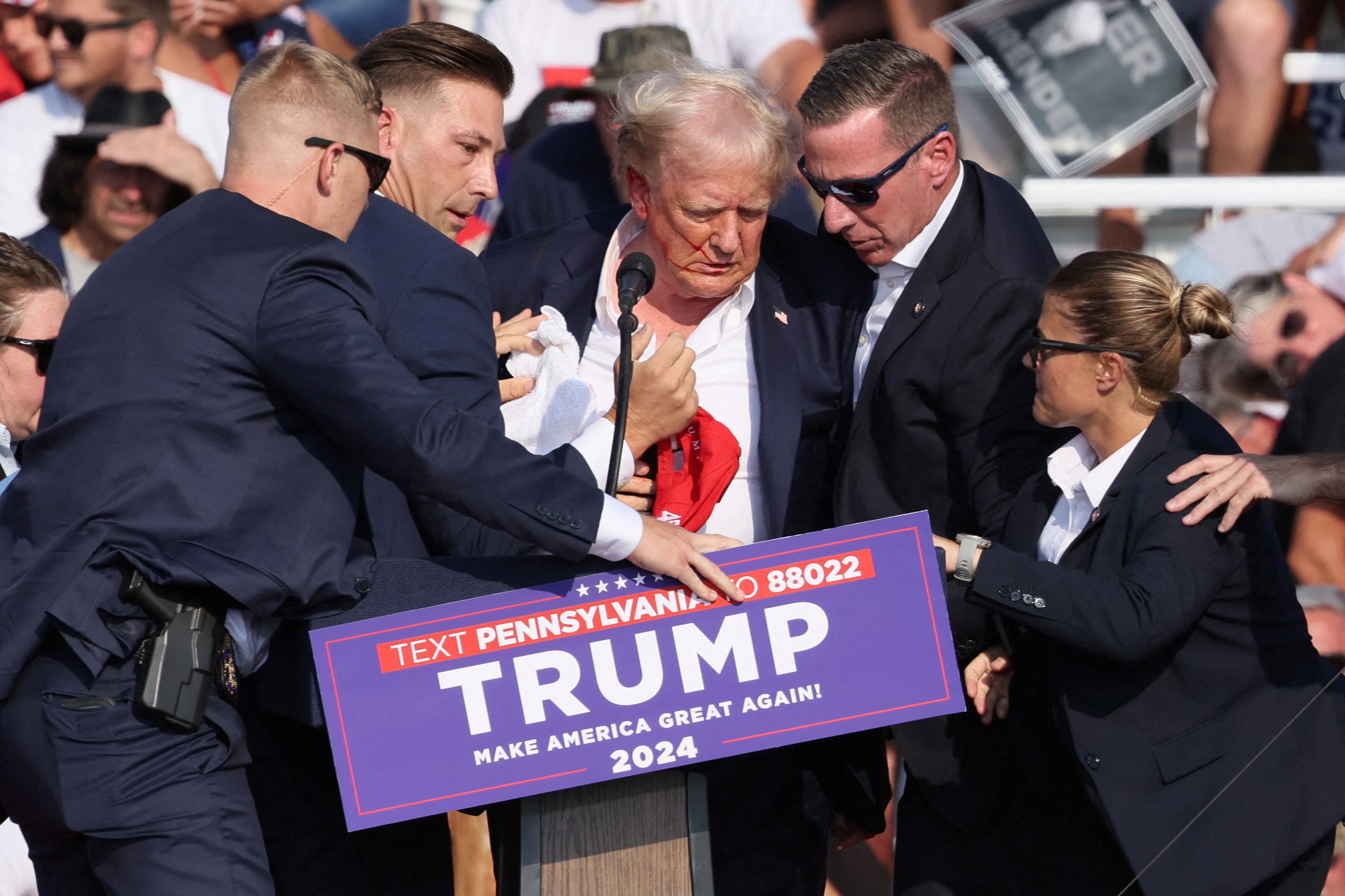 Republican presidential candidate and former U.S. President Donald Trump is assisted by security personnel after gunfire rang out during a campaign rally at the Butler Farm Show in Butler, Pennsylvania, U.S., July 13, 2024. REUTERS/Brendan McDermid     TPX IMAGES OF THE DAY