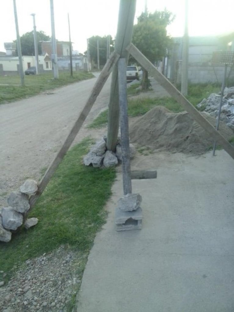 Un basural en medio de un barrio y un poste a punto de caerse