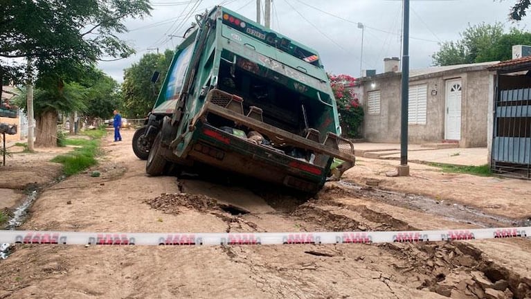 Un camin recolector qued enterrado en un pozo de una calle de tierra