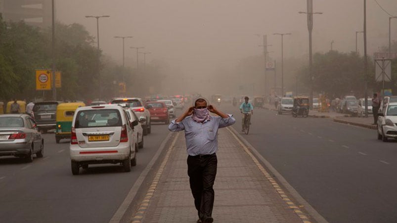 Un hombre se envuelve con una bufanda mientras una tormenta de polvo envuelve la ciudad de Nueva Delhi. Foto: AP 