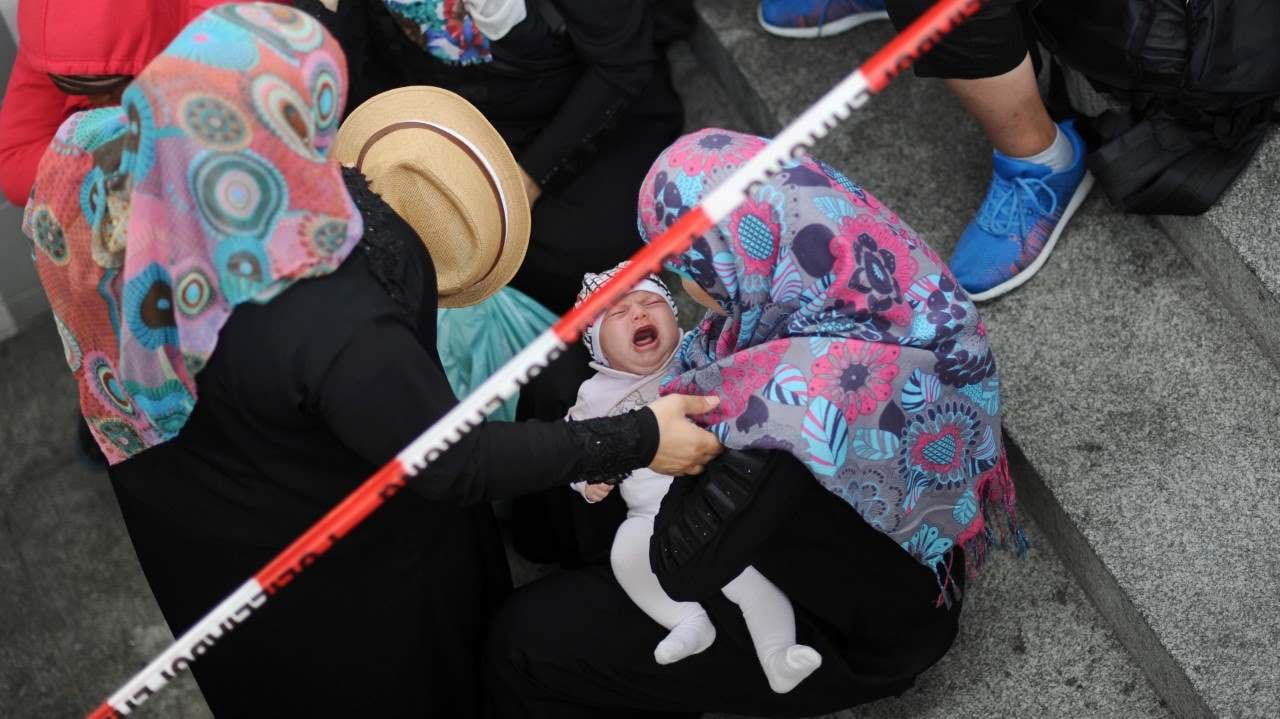 Una mujer siria lleva a un bebé que llora mientras espera a ser registrada, en una oficina, en la estación de trenes de Alemania. Foto: AP