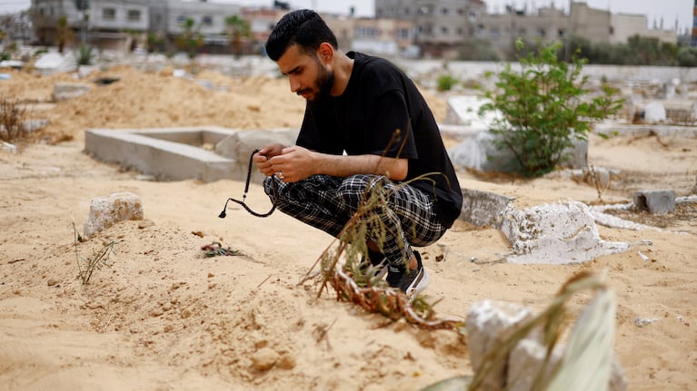 Uncle of Sabreen al-Rouh, a Palestinian baby girl, who died a few days after she was saved from the womb of her dying mother Sabreen al-Sheikh (al-Sakani), killed in an Israeli strike along with her husband Shokri and her daughter Malak, amid the ongoing conflict between Israel and Hamas, crouches next to her grave in Rafah in the southern Gaza Strip, April 26, 2024. REUTERS/Mohammed Salem