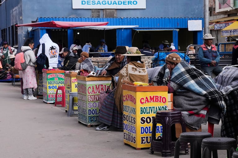 Vendedores que cambian moneda extranjera esperan a clientes en Desaguadero, Bolivia, el martes 14 de octubre de 2025. (AP Foto/Juan Karita)